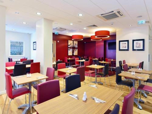 a restaurant with wooden tables and red chairs at Travelodge Glasgow Queen Street in Glasgow