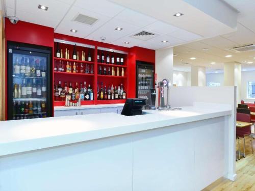 a bar with red walls and a white counter at Travelodge Glasgow Queen Street in Glasgow