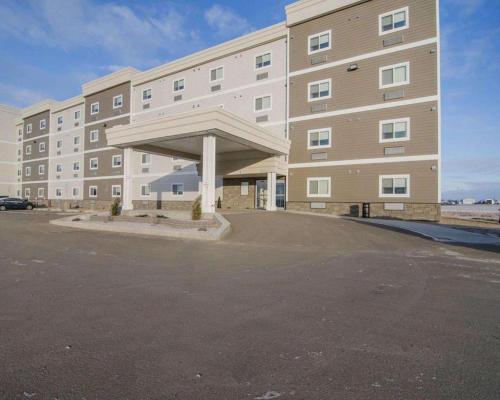 an empty parking lot in front of a large building at Quality Inn and Suites - KindersLey in Kindersley