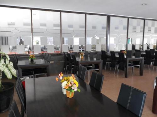 Ima hotel في Klapalima: قاعة اجتماعات بها طاولات سوداء وكراسي وزهور
