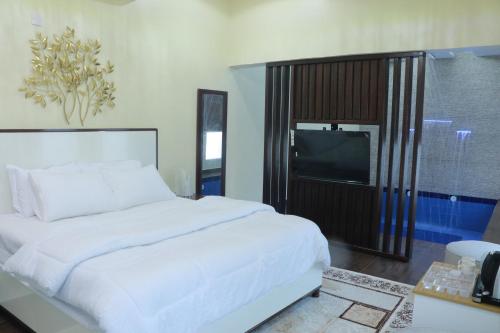 una camera da letto con un grande letto bianco e una televisione di D a Al Ḩamrāʼ