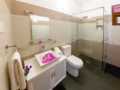 a bathroom with a toilet and a sink with purple flowers at Holiday Home Kalutara in Kalutara