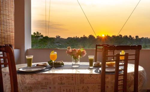 Holiday Home Kalutara في كالوتارا: طاولة مع الطعام وغروب الشمس في الخلفية