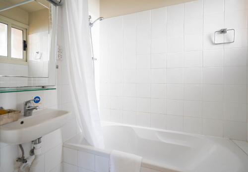 a white bathroom with a sink and a tub and a toilet at Basilica Holiday Resort in Paphos City