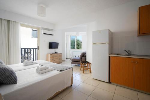 a bedroom with a bed and a kitchen with a refrigerator at Basilica Holiday Resort in Paphos City