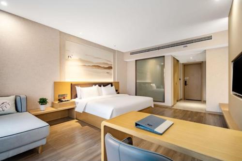 a hotel room with a bed and a desk with a laptop at Huaian Reykana Hotel in Huai'an