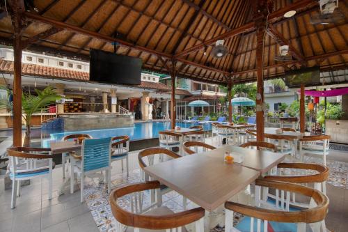 a restaurant with tables and chairs and a pool at Legian Village Hotel - CHSE Certified in Legian
