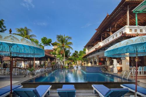 a pool at a resort with chairs and a building at Legian Village Hotel - CHSE Certified in Legian