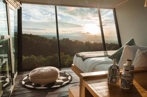 een slaapkamer met een bed en een groot raam bij Aurora Cabins by Panoramika in Jatiluwih