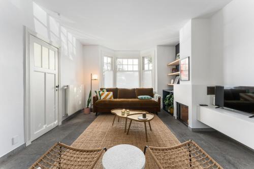 a living room with a couch and a table at Magique 31 - Luxeverblijf met tuin & parking in Oostduinkerke