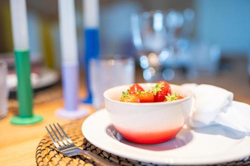a bowl of strawberries on a plate on a table at Magique 31 - Luxeverblijf met tuin & parking in Oostduinkerke