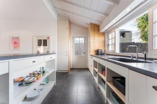 a kitchen with white cabinets and a sink and a window at Magique 31 - Luxeverblijf met tuin & parking in Oostduinkerke