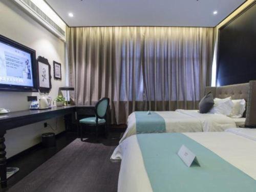 a hotel room with two beds and a desk and a television at Xana Hotelle Shihezi Junken Museum Branch in Shihezi