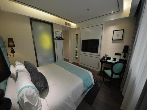 a hotel room with a bed and a desk at Xana Lite Korla Shihua Avenue Longquehe in Korla