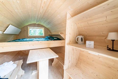 Cabaña de madera con cama y ventana en Camping Marmolada Malga Ciapela, en Malga Ciapela