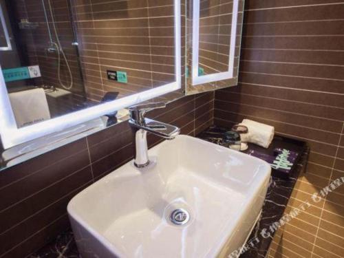 W łazience znajduje się umywalka i lustro. w obiekcie Xana Hotelle Xiamen Airport Zone Government w mieście Heshan