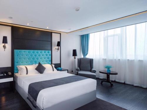 Cette chambre comprend un grand lit et une chaise. dans l'établissement Xana Hotelle Yinchuan Dayuecheng Branch, à Yinchuan