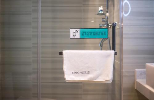 ein Handtuch, das an einer Duschtür im Bad hängt in der Unterkunft Xana Lite Nanchong Pengan Wuxing Garden Branch in Peng'an