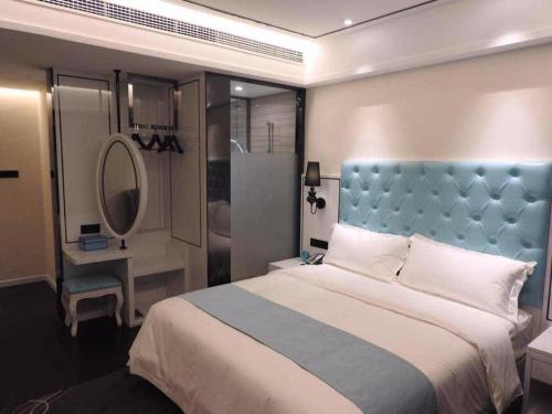 Schlafzimmer mit einem Bett mit blauem Kopfteil und einem Spiegel in der Unterkunft Xana Hotelle Ankang High-Tech High School in Ankang