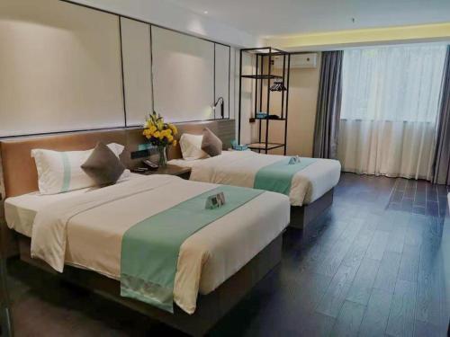 a hotel room with two beds and a mirror at Xana Lite Jiangmen Yingbin West in Jiangmen