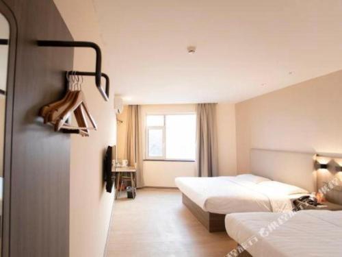 a hotel room with two beds and a window at 7 Days Inn Tianjin Binhai Passenger Station Huabei Ceramics in Binhai