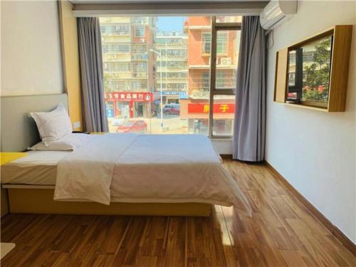 a bedroom with a large bed and a large window at 7Days Inn Changsha University in Xingsha