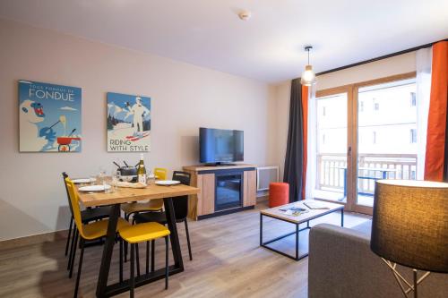 a living room with a table and a tv at Résidence Club MMV Samoens in Samoëns