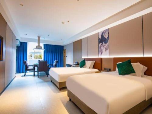 MaogangにあるPai Hotel Zhuhai Xinxiangzhou China Resources Vanguard Minzhu Railway Stationのベッド2台とテーブルが備わるホテルルームです。