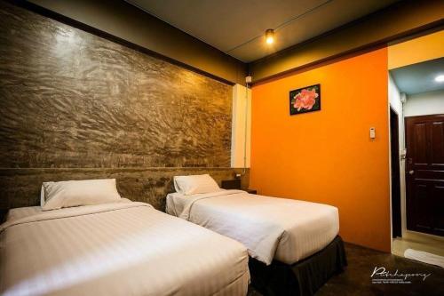 two beds in a room with orange walls at Pornsiri Hotel Sisaket in Si Sa Ket