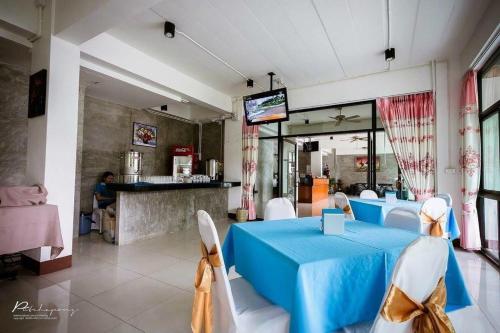 uma sala de jantar com uma mesa azul e cadeiras brancas em Pornsiri Hotel Sisaket em Si Sa Ket
