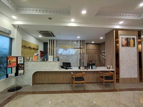 a restaurant with a counter and two chairs in a lobby at Grand City Hotel in Kampong Gadong