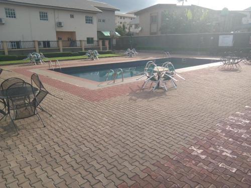 uma piscina com mesas e cadeiras ao lado de um edifício em Neocourts Hotel em Enugu