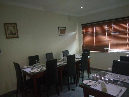uma sala de jantar com mesas e cadeiras e uma janela em Neocourts Hotel em Enugu