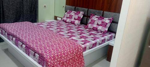 a bed with a pink comforter and pillows on it at Xanadu studio Appartment 904 in kolkata