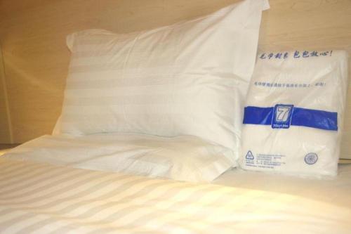 Xiawutun的住宿－7 Days Inn Xingyi Wanfenglin Xiawutun，一张带白色床单的床,上面装有袋子