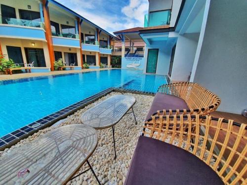 2 sillas y una piscina en un edificio en The Bed Vacation Rajamangala Hotel en Songkhla