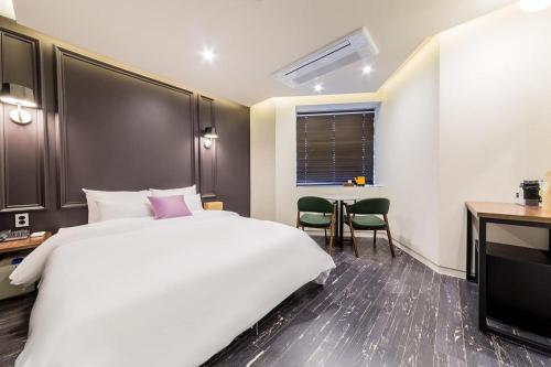 Habitación de hotel con cama grande y escritorio. en Plain Hotel, en Chuncheon