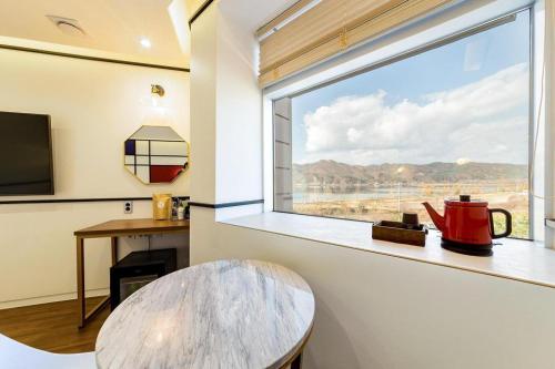 a room with a large window with a table and a desk at Plain Hotel in Chuncheon