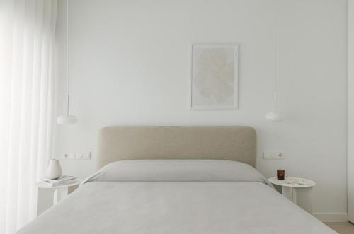 a white bedroom with a bed and two tables at Blanc Residences in Ioannina