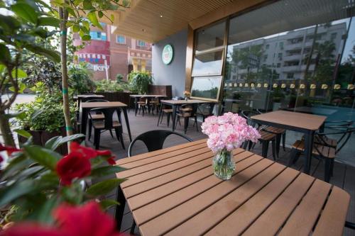 a vase of pink flowers sitting on a wooden table at danfeng kelly hotel in Shenzhen