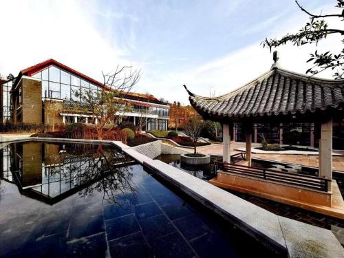 a pool of water with a pavilion and a building at Tiantai He hotel in Tiantai