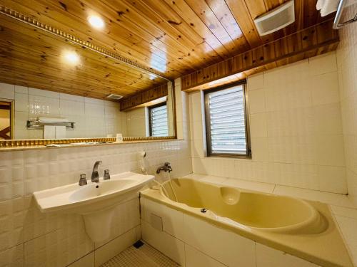 a bathroom with a sink and a tub and a mirror at Ivy Motel in Chiayi City