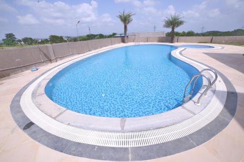 ein großer Pool mit blauem Wasser in der Unterkunft Jha Farm & resorts 