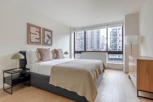 a bedroom with a large bed and a large window at Blueground UW gym doorman nr Central Park NYC-1441 in New York