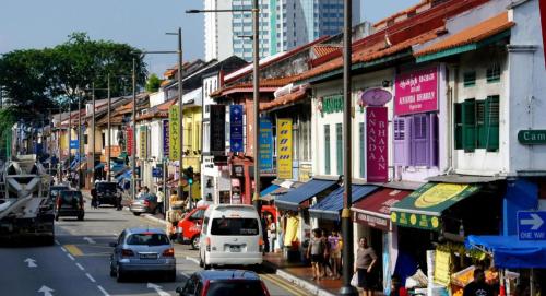 una concurrida calle de la ciudad con coches y gente en la acera en South East Asia Hotel en Singapur