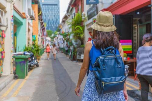 Una mujer con una mochila caminando por una calle en South East Asia Hotel en Singapur