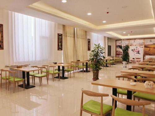 un restaurante con mesas de madera y sillas verdes en GreenTree Inn Zhangye Ganzhou Train Station Orthopaedic Hospital, en Zhangye