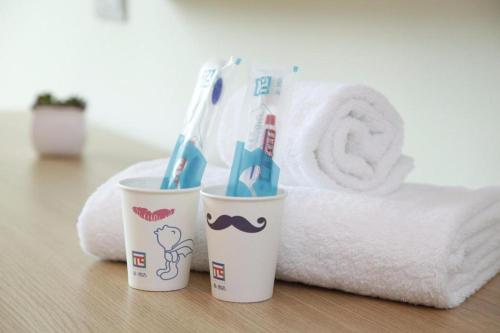 two cups with toothbrushes in them next to a towel at PAI Hotels·Kangding Xiaqiao in Garze