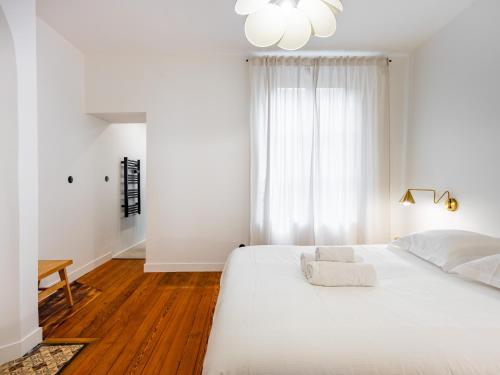 - une chambre blanche avec un grand lit blanc et une fenêtre dans l'établissement Le Chic de Dizier, à Nancy