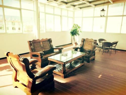 a living room with couches and a table and chairs at PAI Hotels·Ruili Munao Road Bus Terminal Station in Ruili
